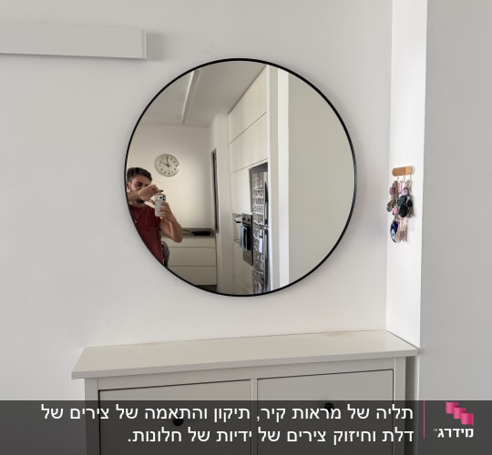 מראה עגולה בעלת מסגרת שחורה דקה תלויה על קיר לבן